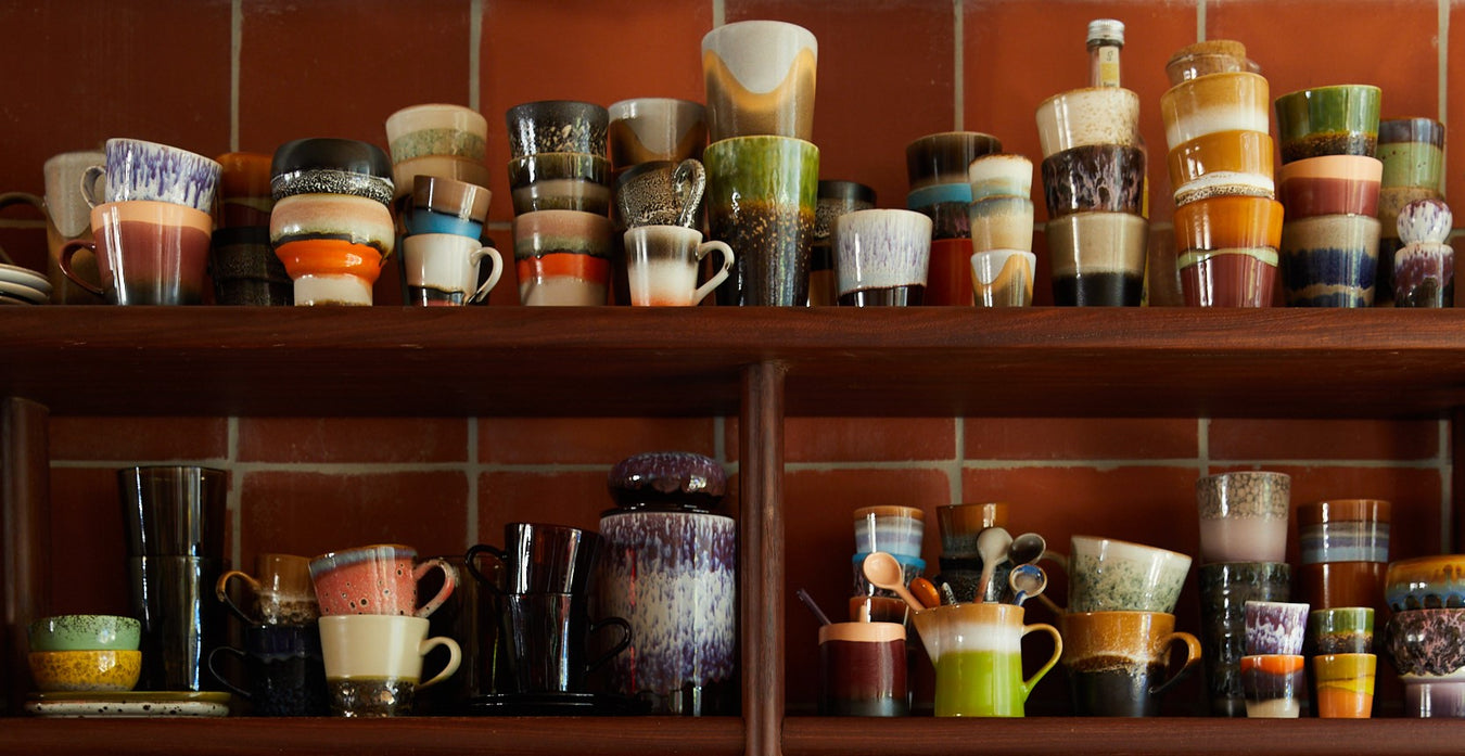 stoneware cups, bowls and spoons on open shelving in retro style kitchen