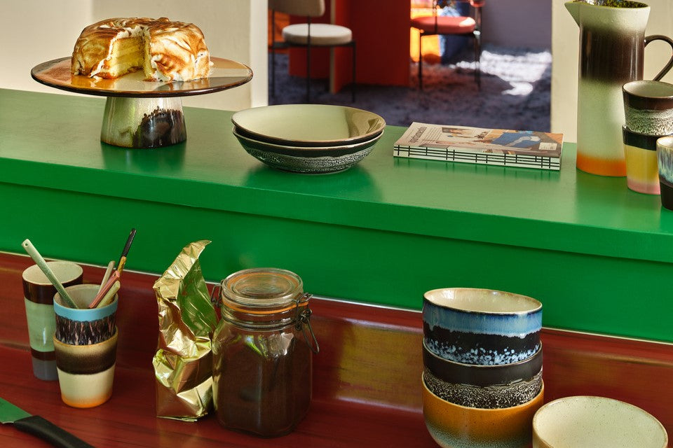 green bar kitchen island with retro style bowls, cups and cake plate