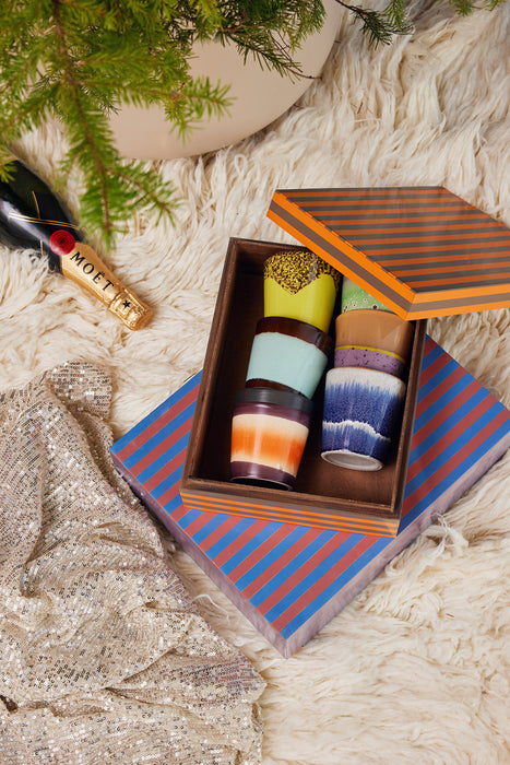 wooden orange and gray striped storage box with ceramic cups and a blue and pink striped box 