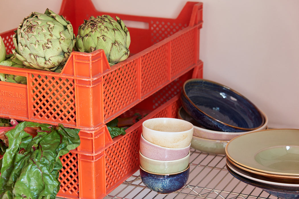 small bowls in cream, pink, green and blue in a pantry with orange crates with produce