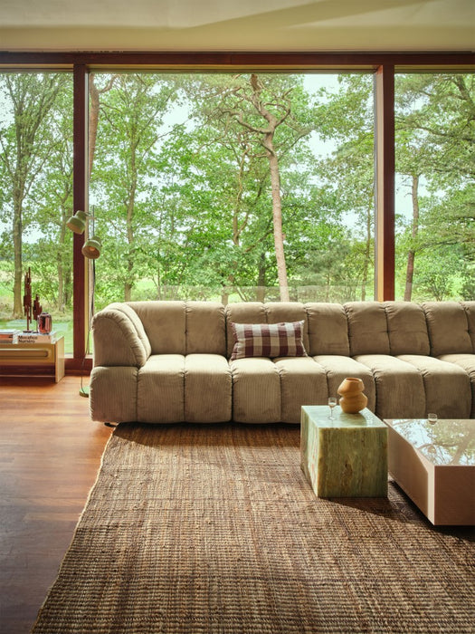 teak wooden skyline sculpture on a low board next to a sectional sofa in front of a large window