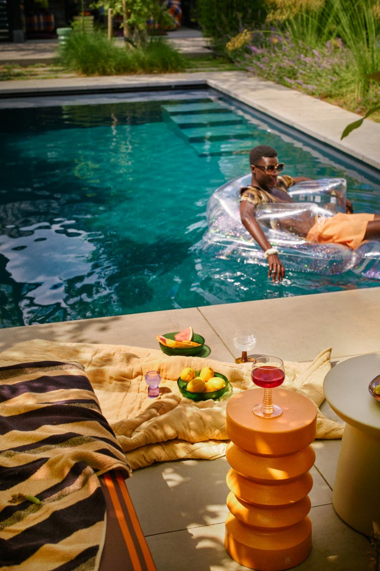 pool with man chilling and an orange terracotta accent table with a glass