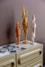 3 wooden skyline sculptures in orange, ochre and beige on a sideboard with polaroids