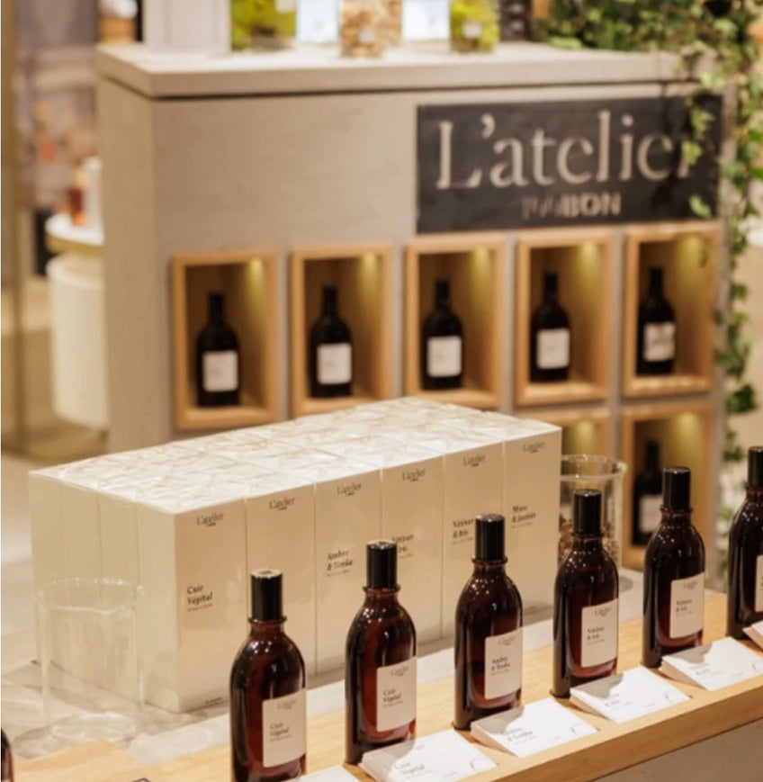 Bottles and boxes on display with 'L'atelier du bon' branding in the background.
