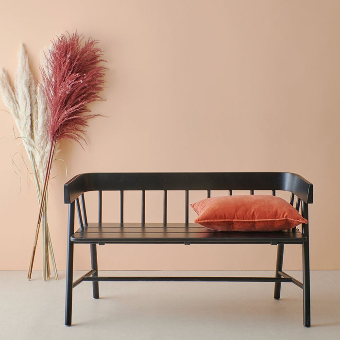 black wooden bench in shaker style in front of a peach colored wall