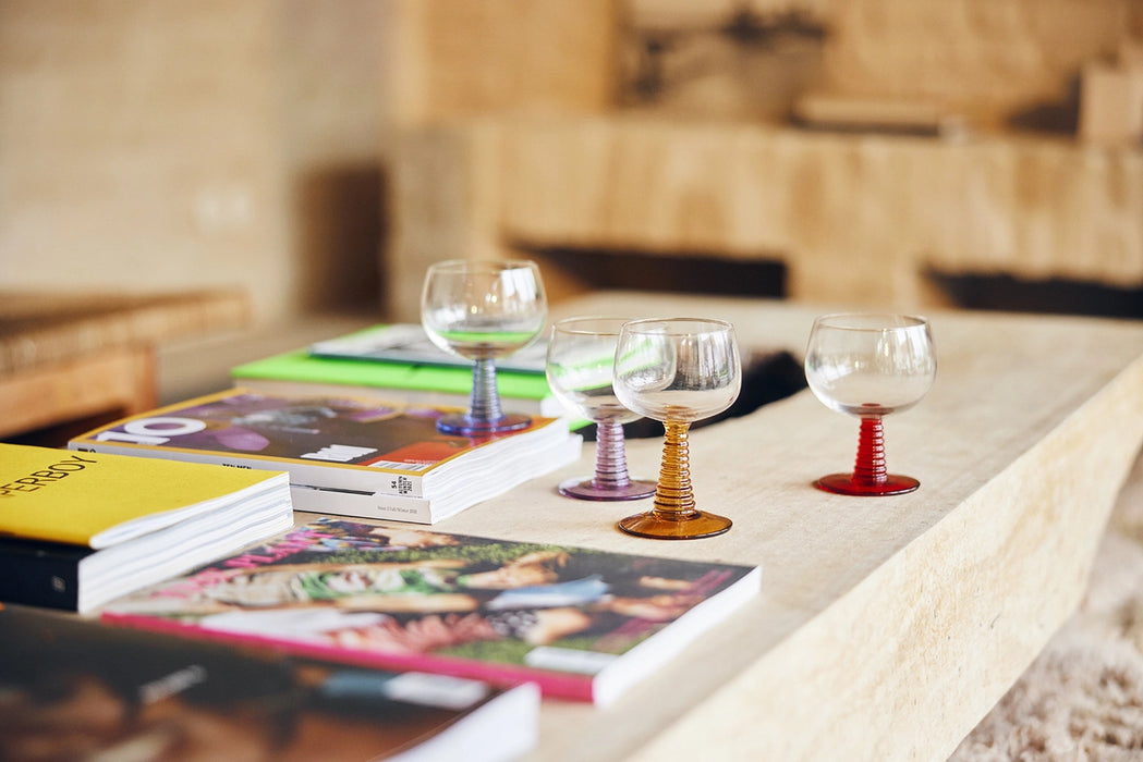 table with books and low stem wine glasses with blue, purple, orange and red stems