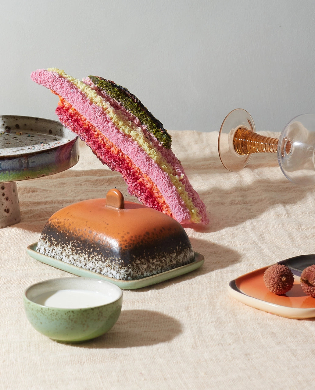 retro style stoneware butterdish in orange brown and green on a table with cake in multiple colors
