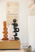 tall black aluminum handmade sculpture with wooden sculpture and ceramic sculpture on a brown table