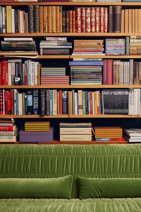 detail of velvet green club couch in front of an open bookshelf filled with books
