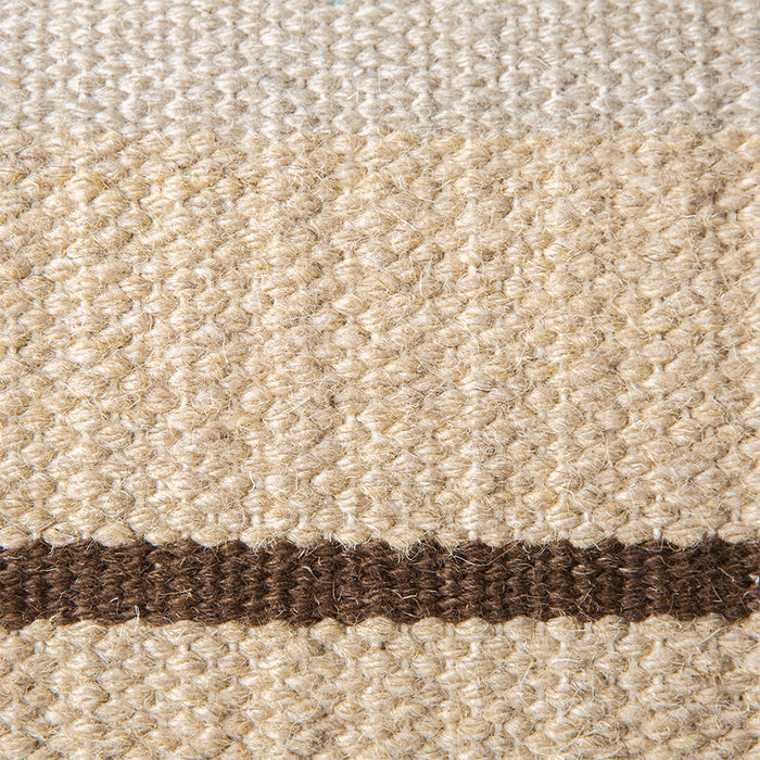 detail of hand woven wool lumbar pillow with one horizontal brown stripe and contrasting green and white piping