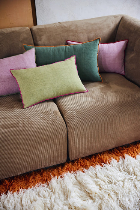 green linen lumbar pillow with pink cotton trim on a brown corduroy couch with other color pillows