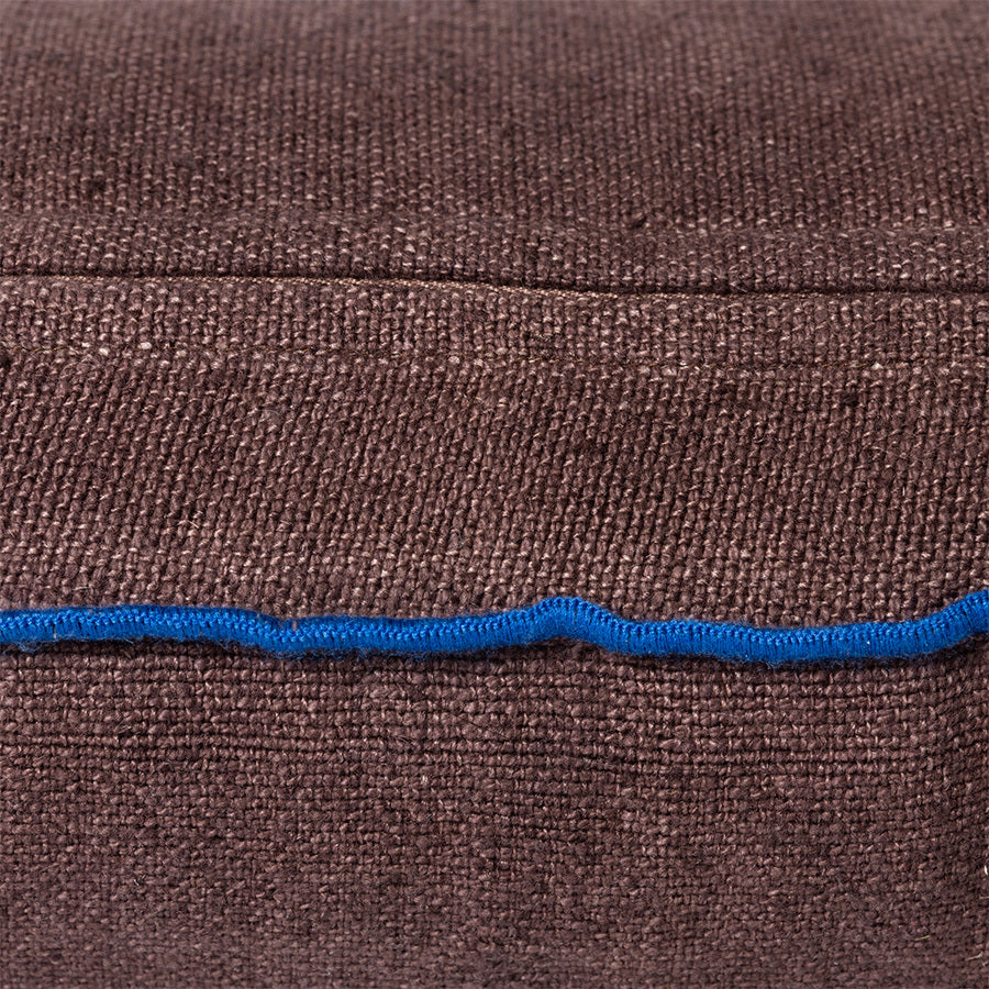 detail of brown linen lumbar pillow with blue cotton trim