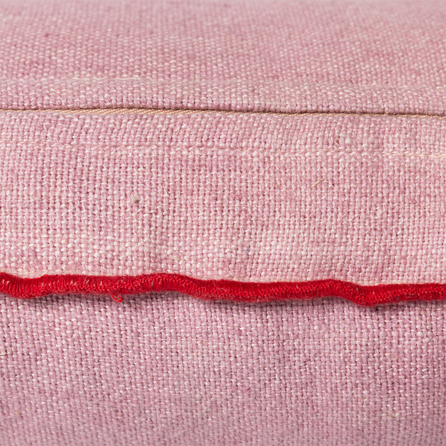 detail of pink linen lumbar pillow with red cotton trim