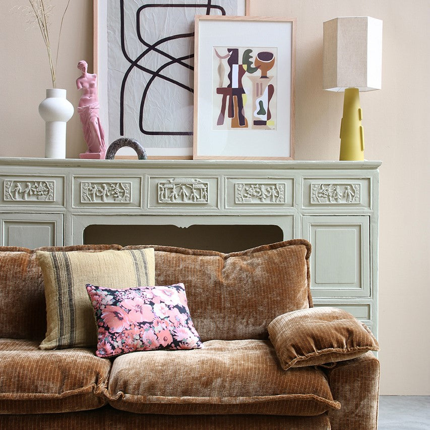 retro style brown corduroy sofa with mustard green table lamp with hexagon shape shade on a soft green fireplace mantel