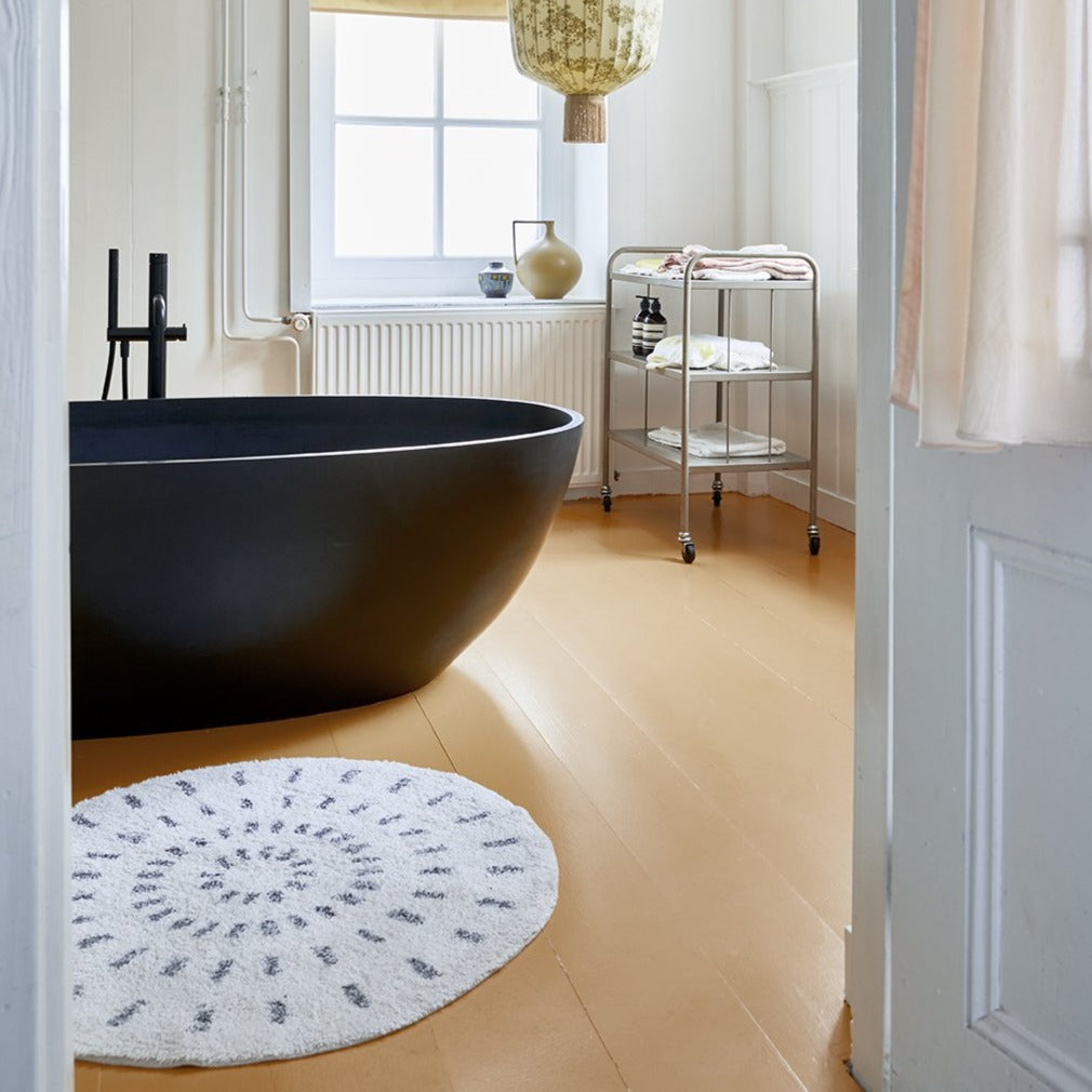 bathroom with black and white round rug in front of black bath tub