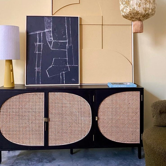 sideboard with cane webbing details and abstract art in black and yellow