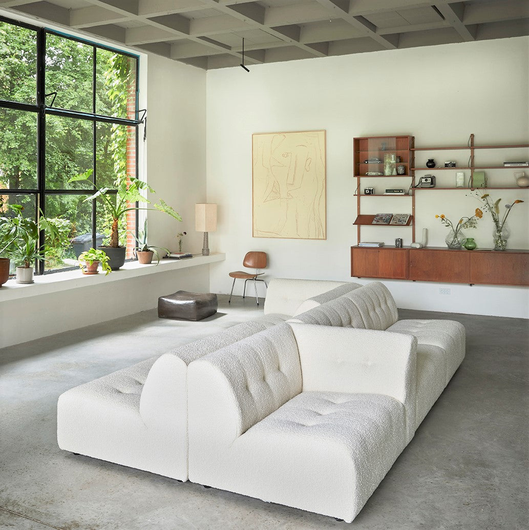 white boucle sofa with open shelving display cabinet and clear glass cloud vases with yellow flowers