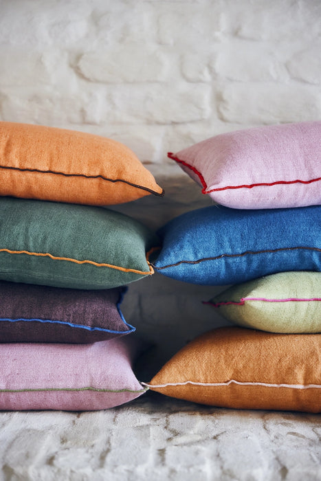 orange, green, purple, pink and blue linen pillows on a stack with contrasting cotton trim