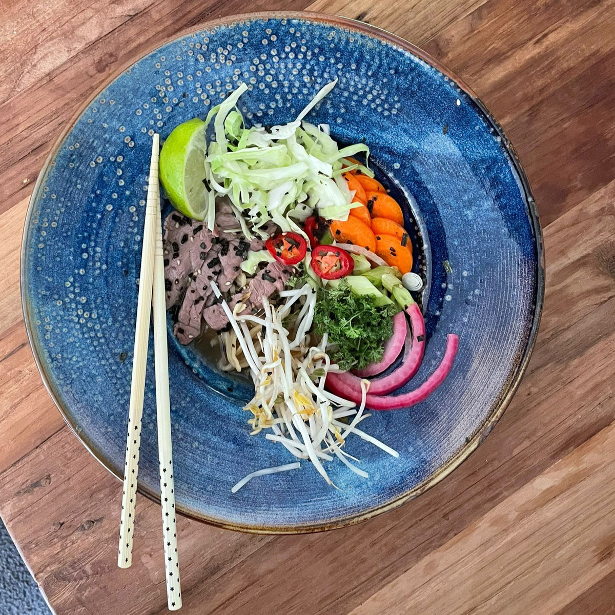 blue porcelain deep pasta plate with vegetables and beef