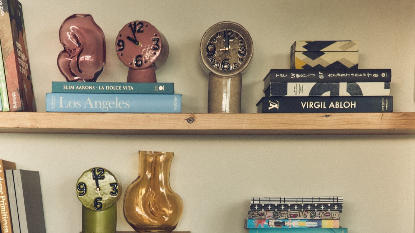 open shelving with ceramic clock, glass vase and books