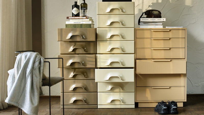 Nordic style drawer cabinet with art work in ochre yellow, sand colored circle vase and a terracotta lamp base with beige shade