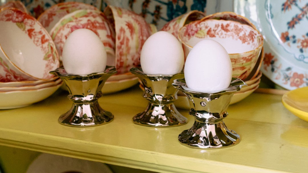silver egg cups with white eggs on yellow shelving