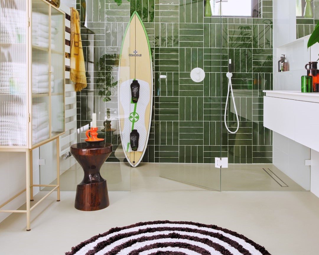 bathroom with green tiles in shower round black and white bath rug and wooden stool