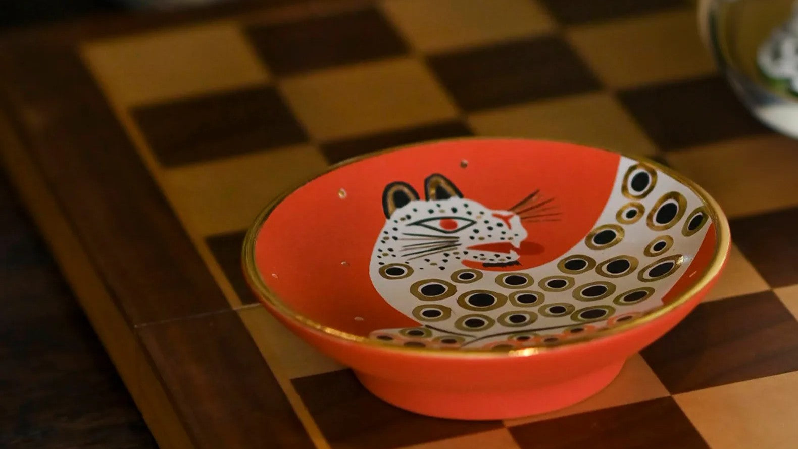 orange bowl with white black and gold tiger on a chess board