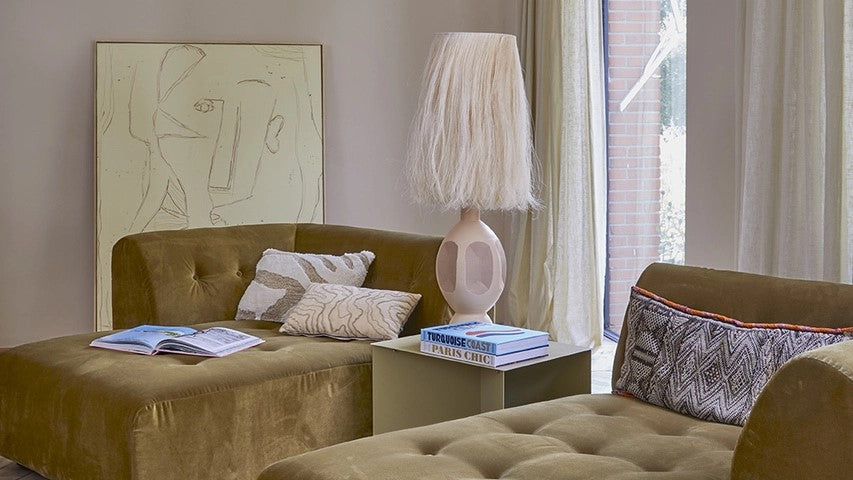 abstract painting, brown daybeds and a bohemian style table lamp 
