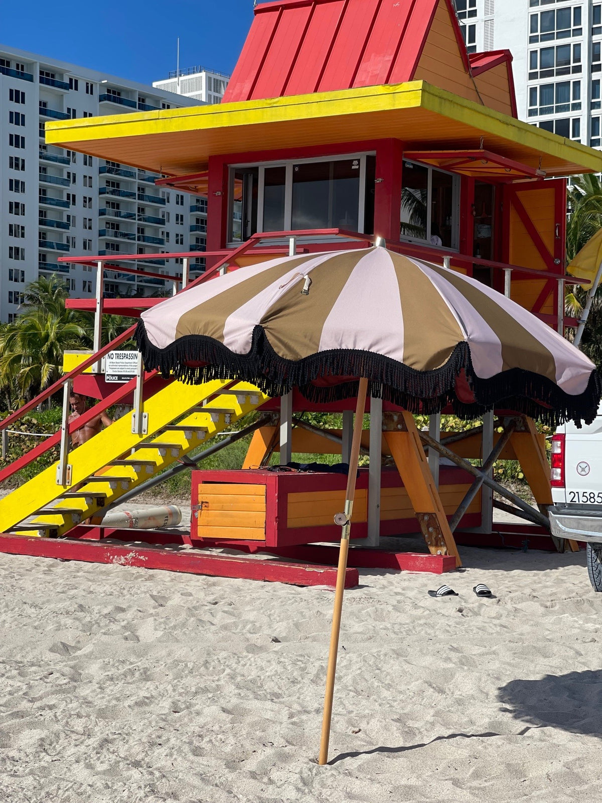 mustard and nude striped parasol with wooden pole on beach in miami