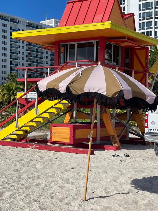 mustard and nude striped parasol with wooden pole on beach in miami