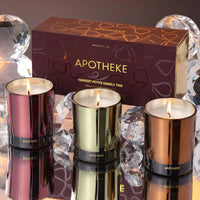 Three lit candles in metallic containers with a 'Apotheke' box in the background.