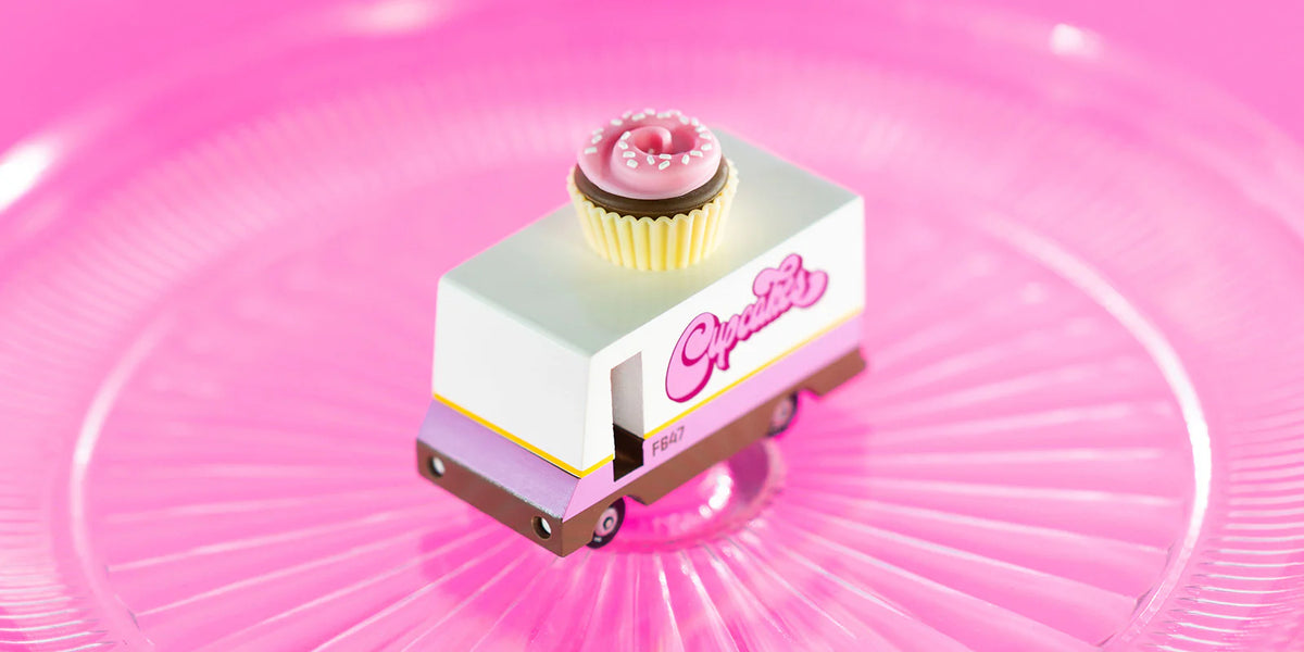 Small toy truck with a cupcake on top against a pink background