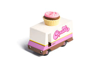 Toy truck with a cupcake on top, resembling a bakery vehicle, on a white background.