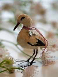 Decorative stork ornament with a string on a blurred natural background
