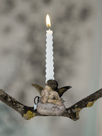 Antique candle holder clip shaped of angel on cloud on a branch with a blurred background