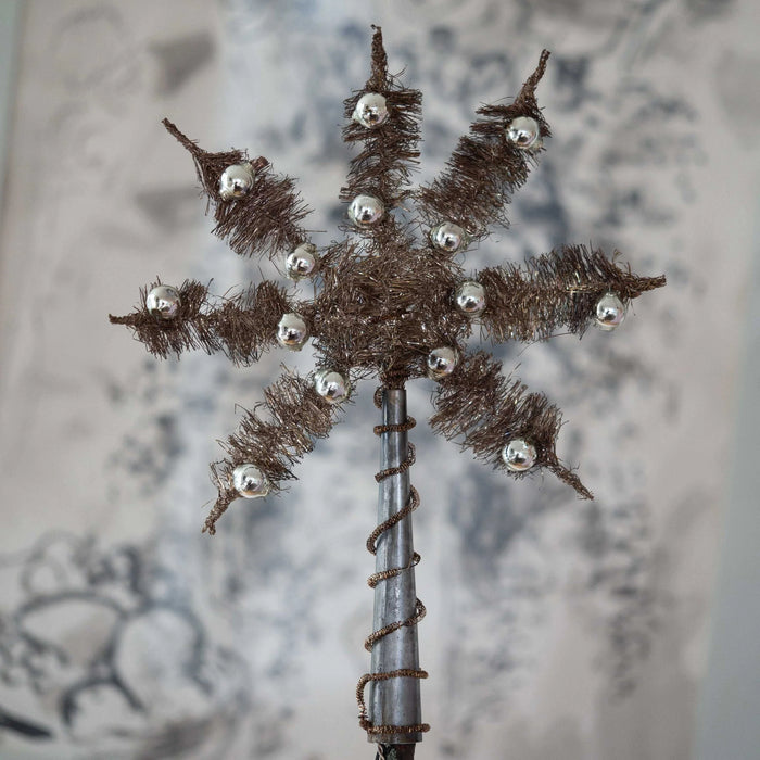 Decorative tinsel with silver beads star Christmas tree topper on a textured background