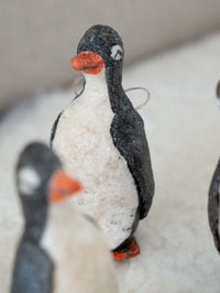 Felt penguin ornament with a red beak on a white background