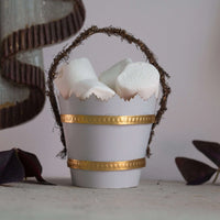 Decorative white bucket with gold band holding marshmallows on a neutral background