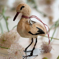 Decorative stork ornament with a string on a floral background