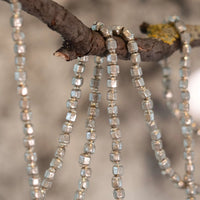 Close-up of a decorative garland with hexagonal beads on a wooden branch.