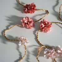 Decorative floral garland with pink flowers and gold wire on a light background