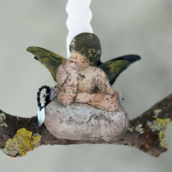 Small angel figurine sitting on a branch with a blurred background