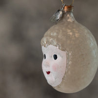 Glass ornament with a face painted on it against a blurred background