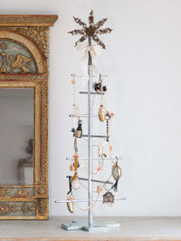 Metal Christmas tree with decorative items against a white wall.