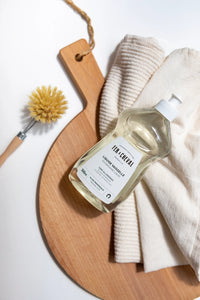 Bottle of cleaning solution on a wooden board with a scrubber and towel