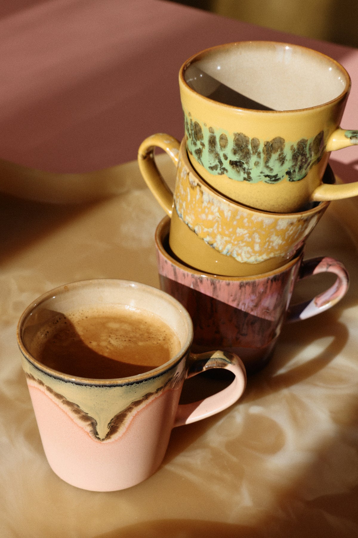 Stack of ceramic coffee cups with different patterns on a wooden surface
