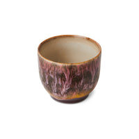 Ceramic cup with a unique glaze pattern on a white background