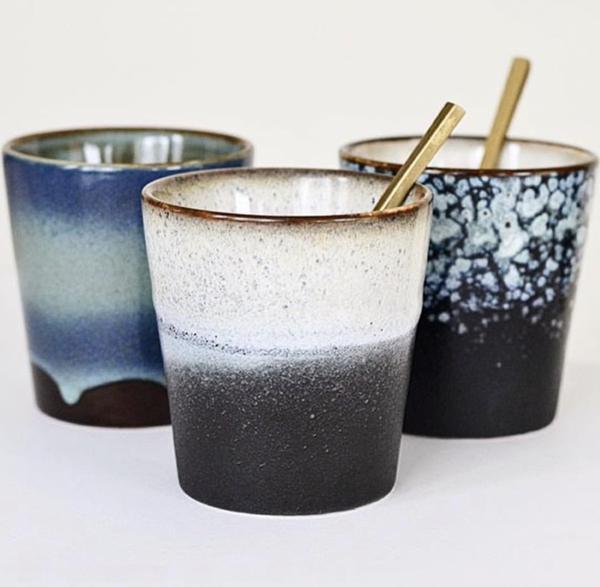 Three ceramic cups with gradient colors and gold straws on a white background
