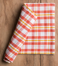 Folded red and white checkered napkin on a wooden surface